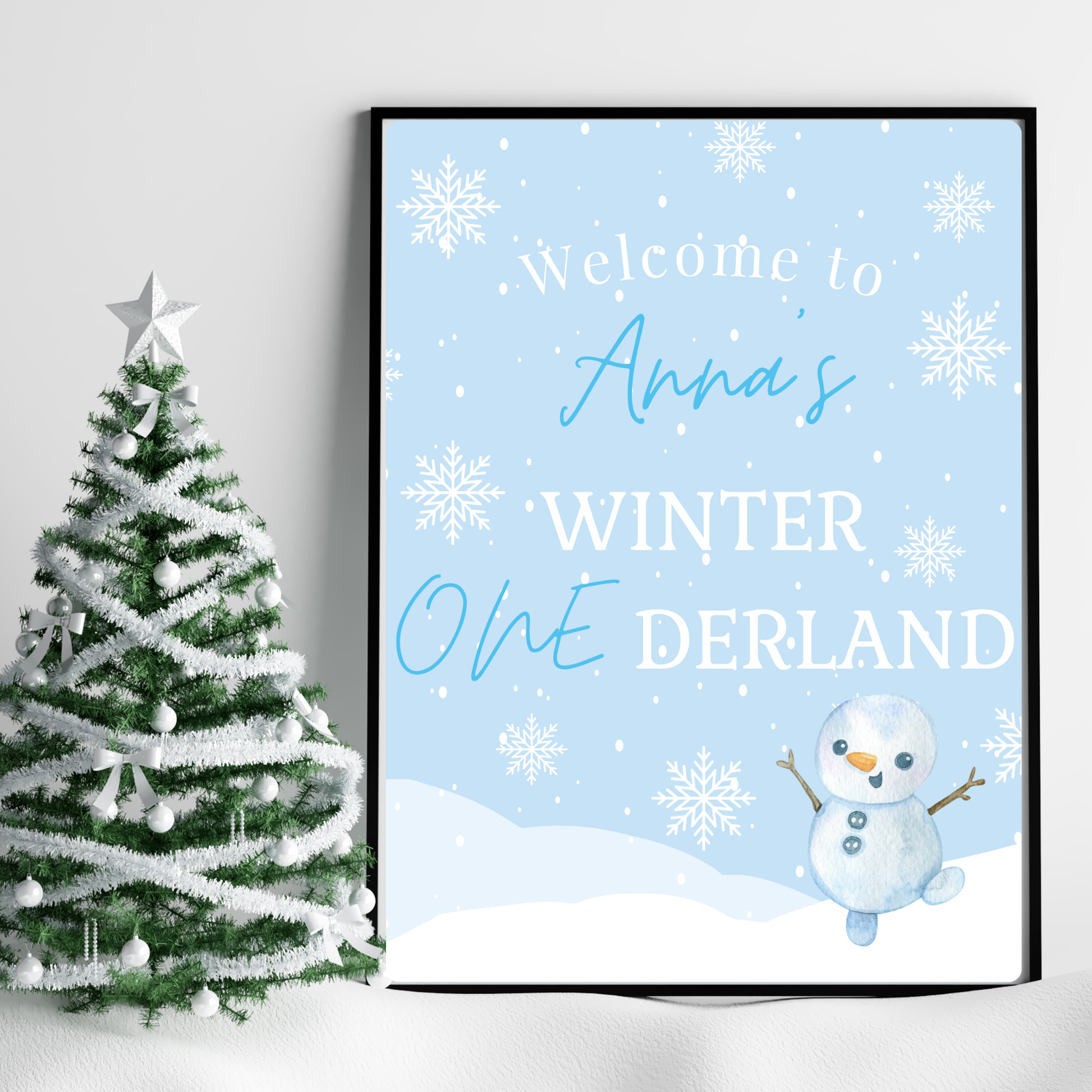Framed winter-themed poster with a snowman and text next to a decorated Christmas tree.