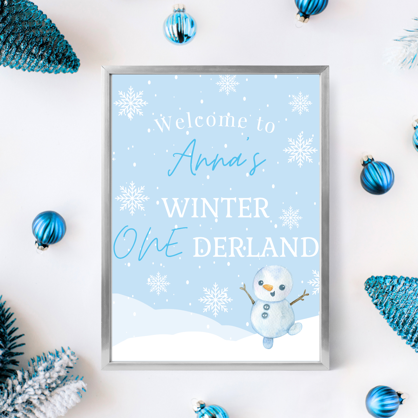 Framed print with 'Welcome to Anna's Winter Onederland' text and snowman illustration, surrounded by winter-themed decorations.